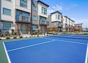 Thumbnail 2 of 9 - A tennis court is surrounded by apartment buildings.