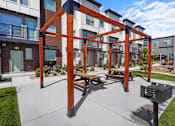 Thumbnail 3 of 9 - A wooden pergola with benches is in the foreground of a residential area.