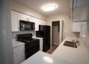 Thumbnail 3 of 11 - a kitchen with black appliances and white counter tops