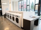 Thumbnail 4 of 23 - a row of washers and dryers in a laundromat with a sink