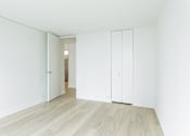 Thumbnail 2 of 8 - A white room with a wooden floor and a white door.