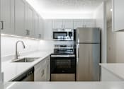 Thumbnail 4 of 8 - A modern kitchen with stainless steel appliances and white cabinetry.