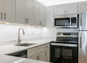 Thumbnail 6 of 8 - A modern kitchen with a stainless steel refrigerator, oven, and microwave.
