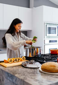 a woman cooking food in a kitchen at ReVive Apartments, Washington, 98424
