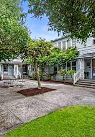A courtyard with a bench and a tree in front of a building.