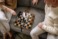 two people sitting on a couch playing chess