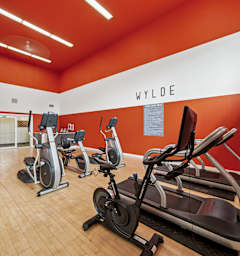 A gym with a row of exercise bikes and a television.