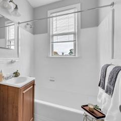 A white bathroom with a wooden cabinet and a white tub.