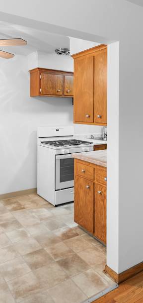 A kitchen with a fan and wooden cabinets.