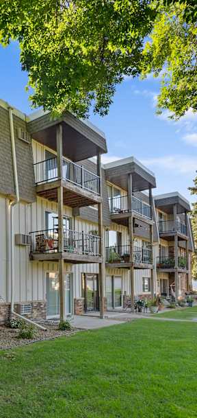 A row of apartment buildings with balconies and potted plants on the front.
