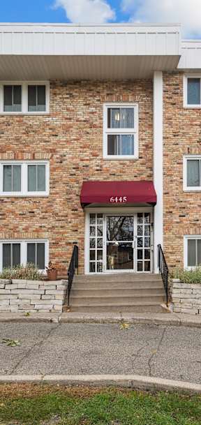 A red awning is on the front door of a brick building.