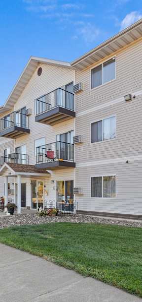 A modern apartment building with a balcony on the second floor.