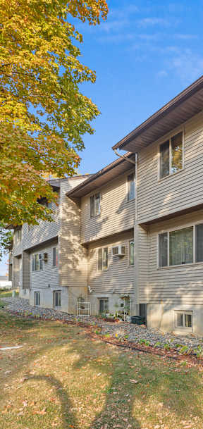A house with a grey siding and a brown roof with a tree in the front.