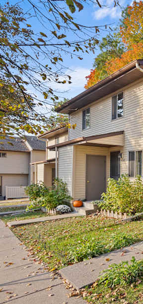 A beige house with a brown door and a small front yard.