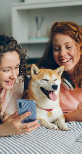two girls with a dog on a bed at Bradford Gwinnett Apartments in Norcross, GA