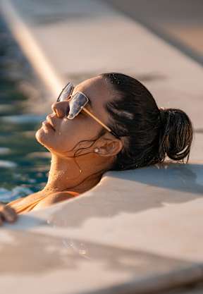A woman in sunglasses is relaxing in a pool.