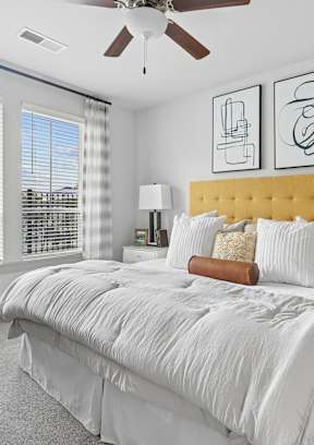 A bedroom with a large bed, a chair, and a ceiling fan.