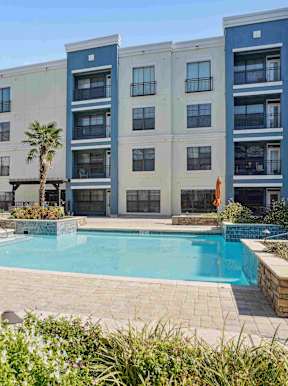 a swimming pool in front of an apartment building with a blue pool