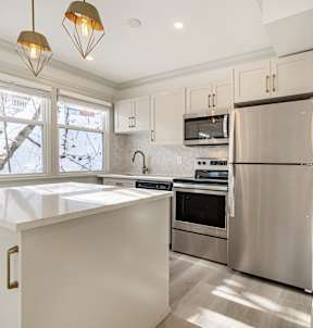 A kitchen with a stainless steel refrigerator and a white countertop.