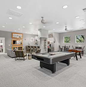 A spacious room with a pool table and a bar area.