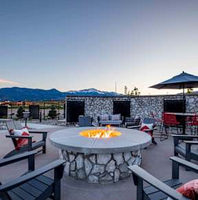 a fire pit on a patio with chairs and tables