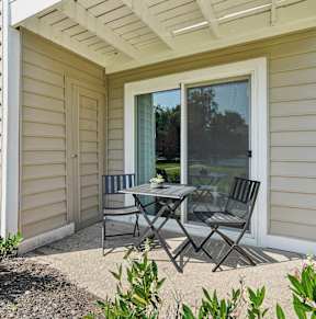 a patio with two chairs and a table in front of a house