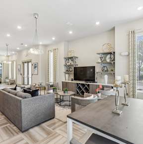 A well-lit, spacious living room with a grey sofa and a grey coffee table.