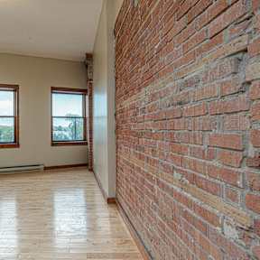 A room with a brick wall and wooden flooring.