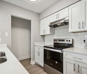 A kitchen with white cabinets and a stove top oven.