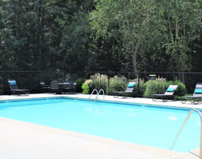 a swimming pool with black chairs and a fence around it at Hidden Creek, Morrow, GA