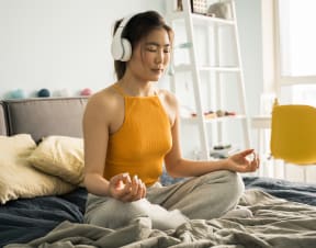 a woman sitting on a bed with headphones on and meditating royalty free meditation stock illustration