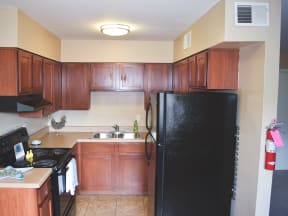 a kitchen with wooden cabinets and a black refrigerator
