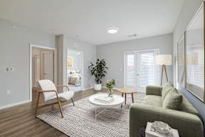 A living room with a grey couch, a white coffee table, a wooden chair, and a potted plant.