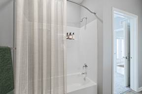 A white bathroom with a green towel hanging on the side.