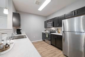 A modern kitchen with a stainless steel refrigerator and black cabinets.
