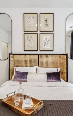A bedroom with a large bed and a tray with a bottle and glass on it.