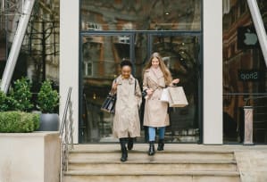 two women walking out of a building with shopping bags