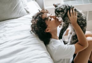 a woman laying in bed with a cat on her face