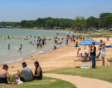 A sunny day at the beach with people enjoying the water and the sand.