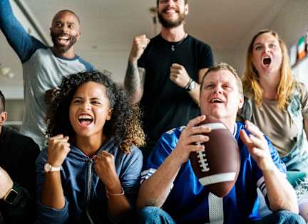 A group of people are watching a football game and cheering.