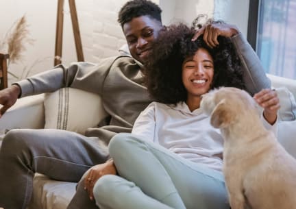 a man and woman sitting on a couch with a dog