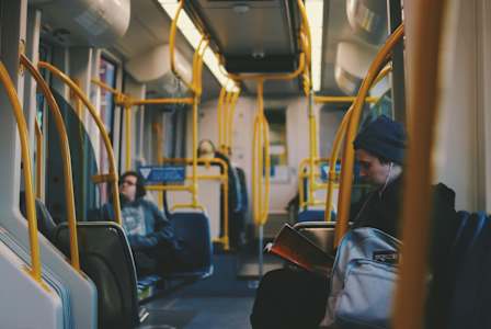 A man is sitting on a bus, reading a book.