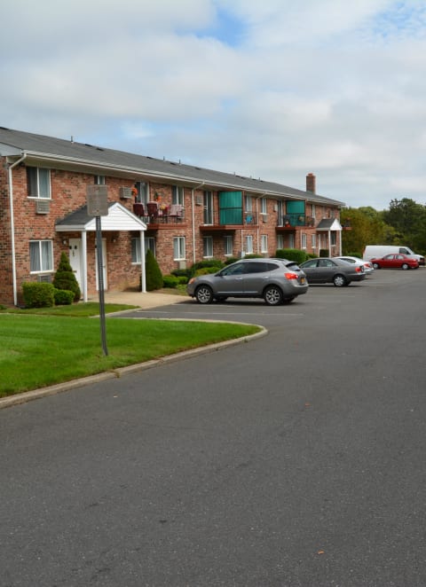 a large brick building with cars parked in front of it at Brookwood at Holbrook, New York, 11741