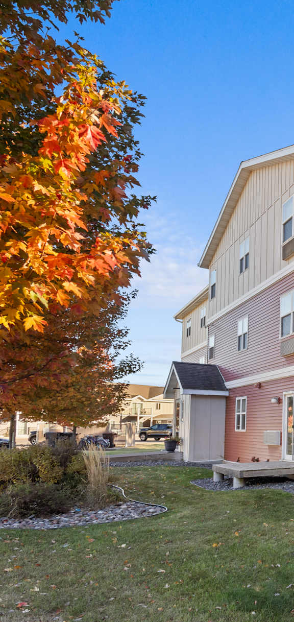A red and beige building with a tree in front.