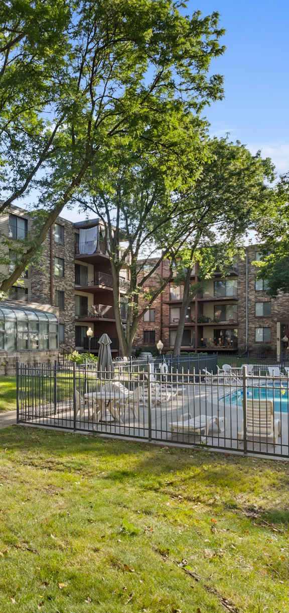 A sunny day at a residential complex with a pool and green lawn.