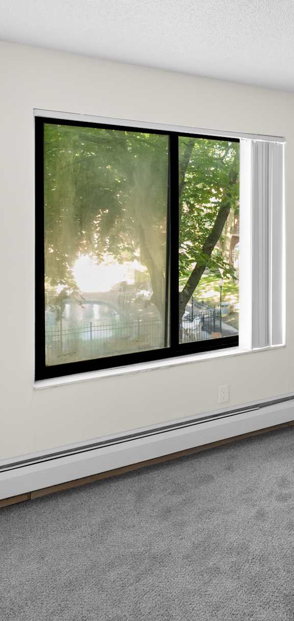 A room with a window and a grey carpet.