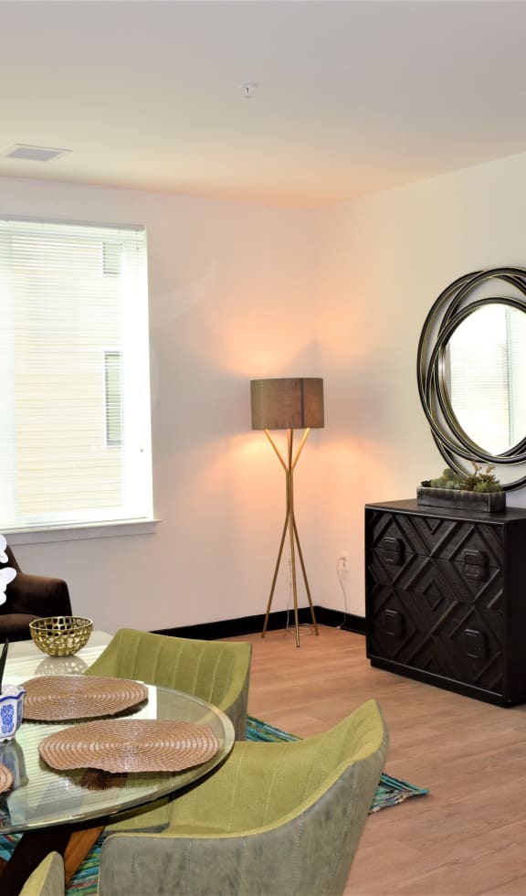 a living room with a table and chairs and a mirror on a dresser