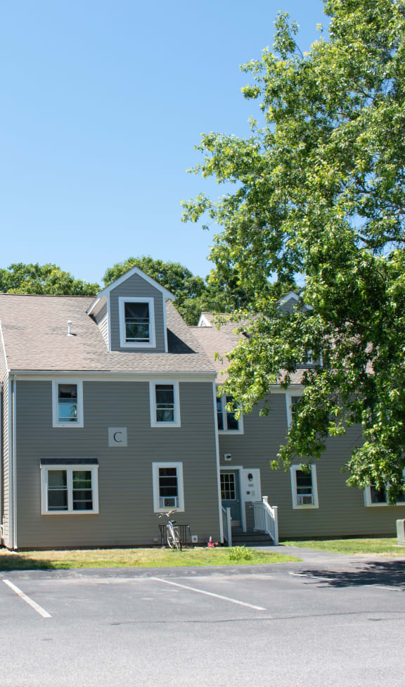 a large gray house with trees in a parking lot
