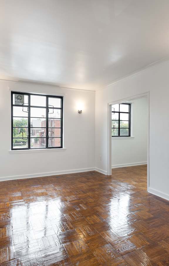 A room with wooden floors and two windows.