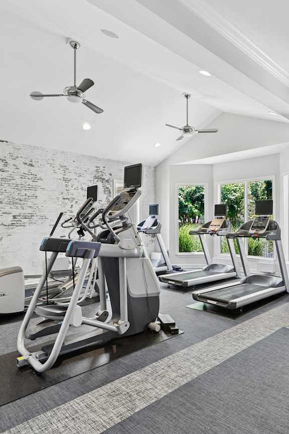 A gym with treadmills, exercise bikes and a swimming pool.